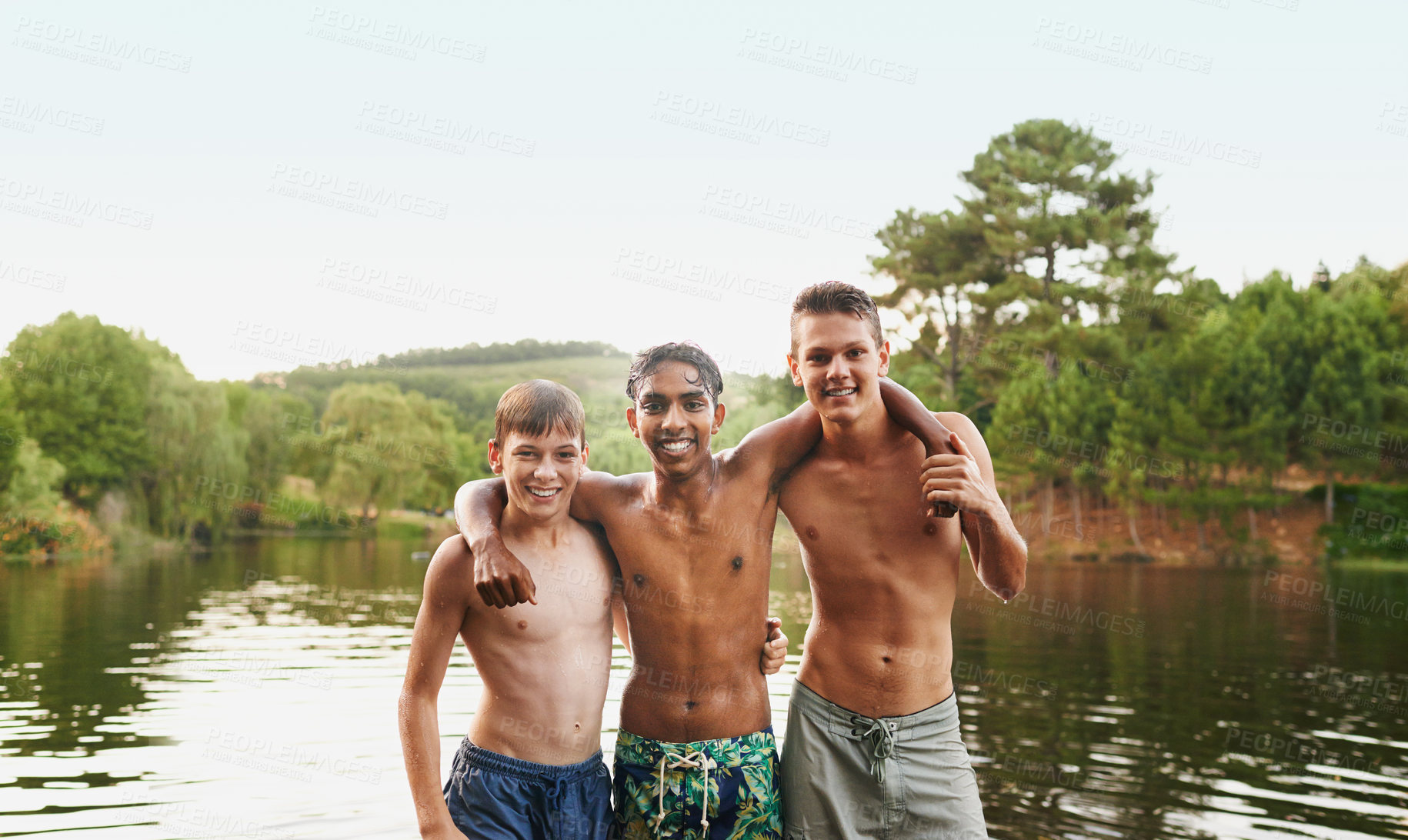 Buy stock photo Portrait, hug and friends happy in swimwear by lake, river and water outdoor in nature, landscape and forest. People, teenage boys and diversity on vacation, holiday and camping trip for summer