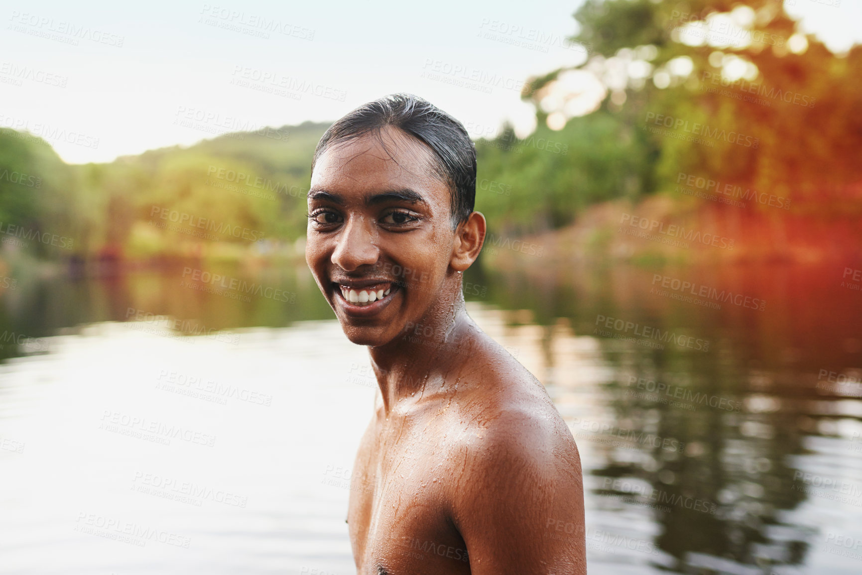 Buy stock photo Portrait, lake and young man swimming in water, vacation and holidays in country side. Smile, joy and sunshine in summer for Indian male person, camp and dam for outdoor adventure in rural area 