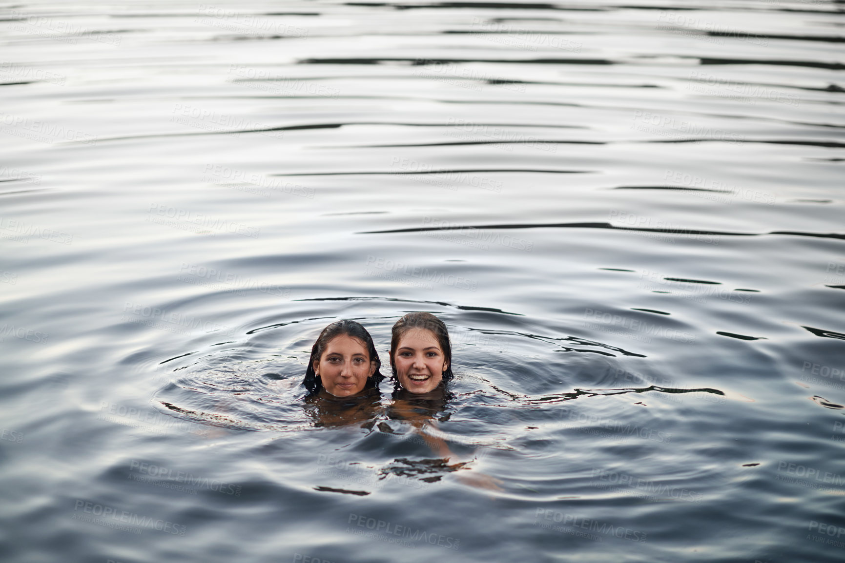 Buy stock photo Shot of two teenage girls swimming in a lake