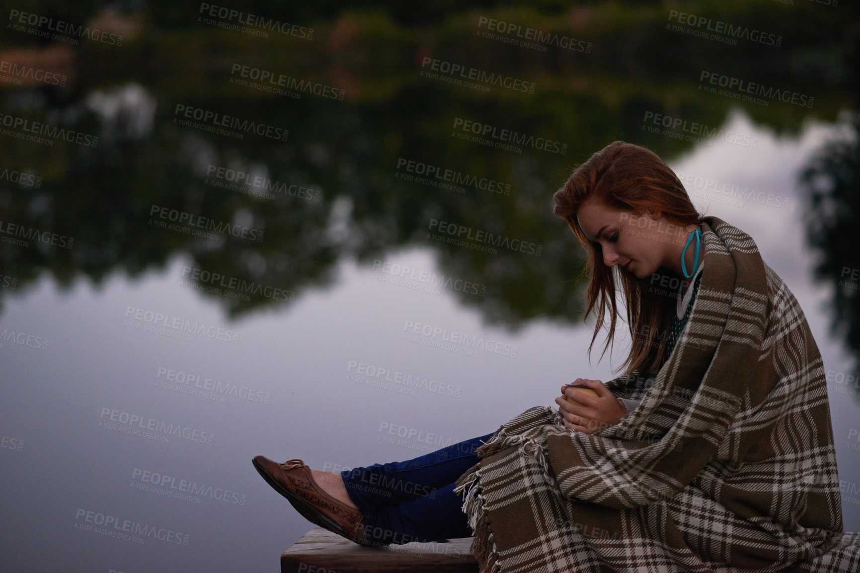 Buy stock photo Blanket, coffee and woman by lake for travel, vacation or holiday with outdoor camping in nature. Calm, water and young female person sitting with morning cappuccino by river or pond in forest.