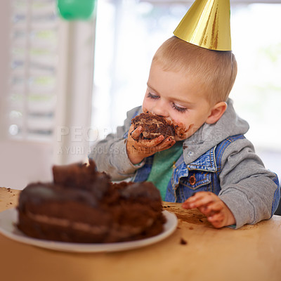 Buy stock photo Cropped shot of a young boy eating his birthday cake before the party
