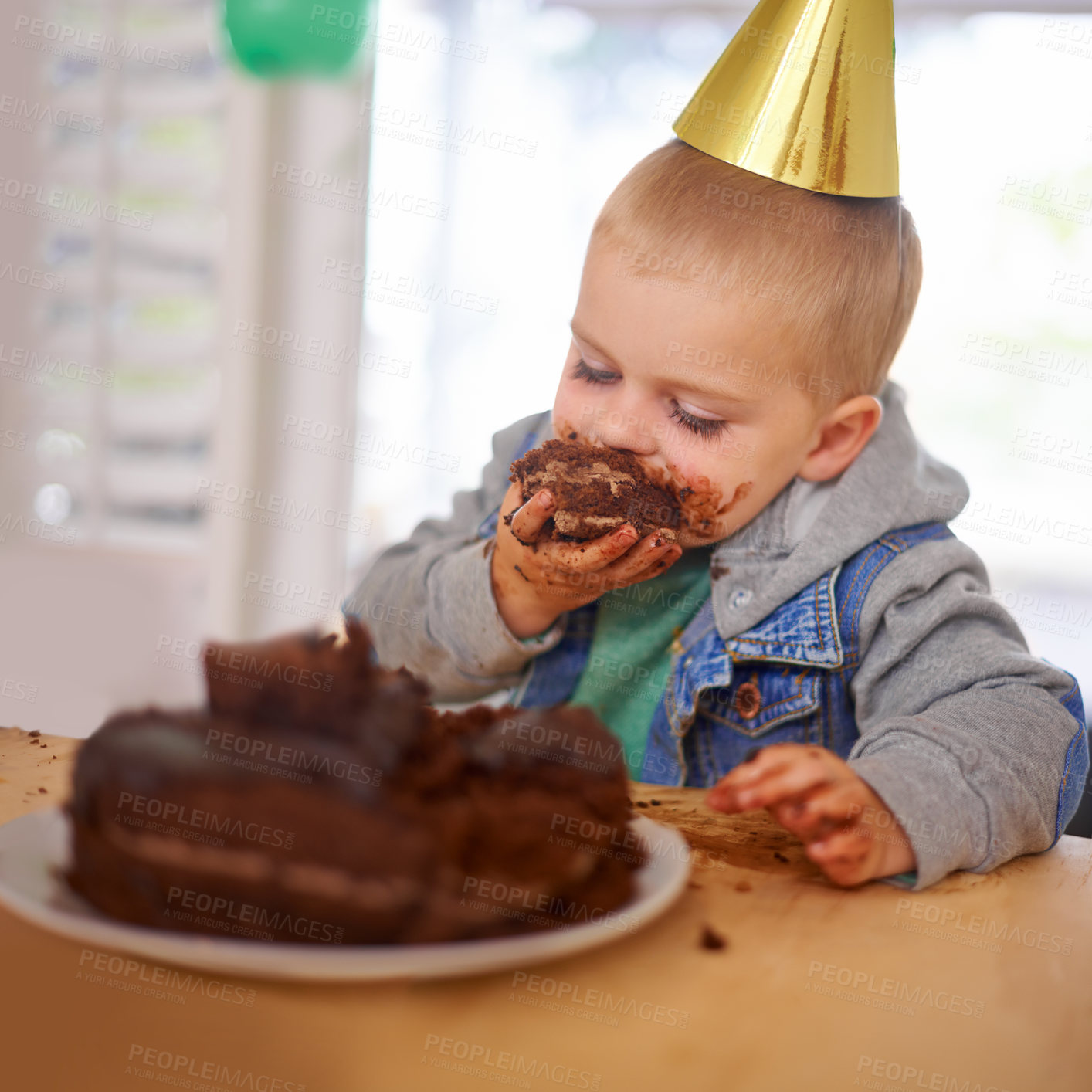 Buy stock photo Cropped shot of a young boy eating his birthday cake before the party