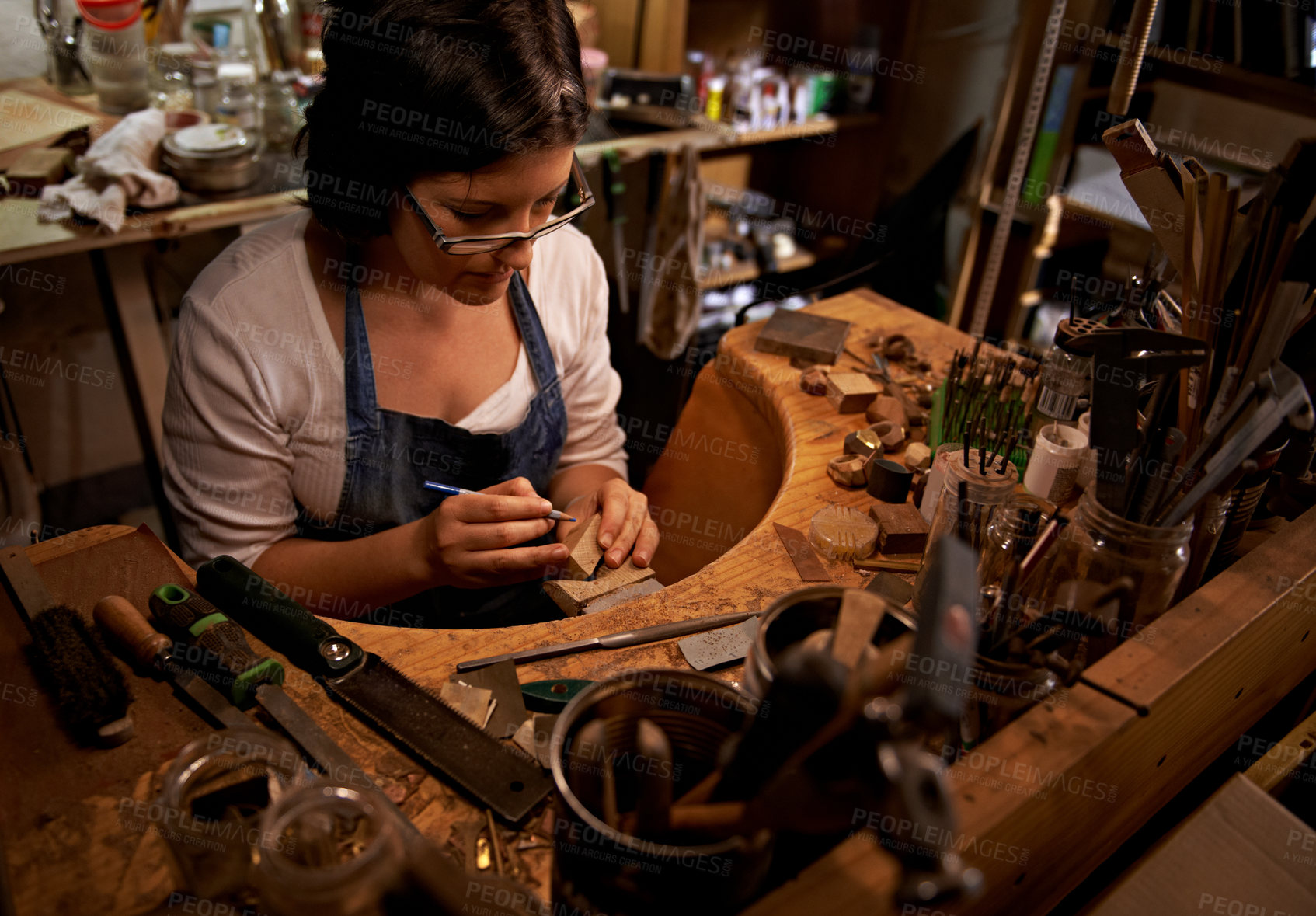 Buy stock photo Woodworking, tools and artist in workshop with creative project or sculpture on table at night. Artisan, carpenter and woman with talent for creativity in dark studio in process of carving wood