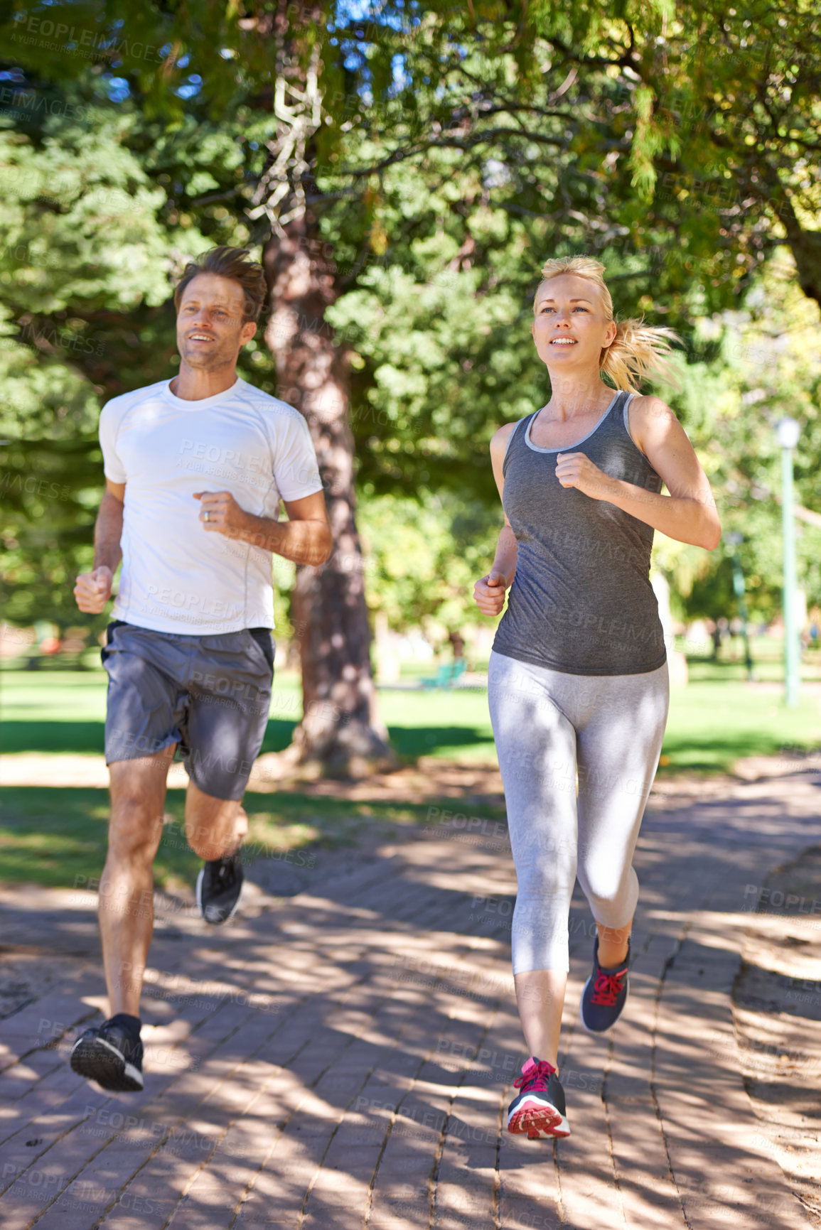 Buy stock photo A couple in sportswear jogging through the park