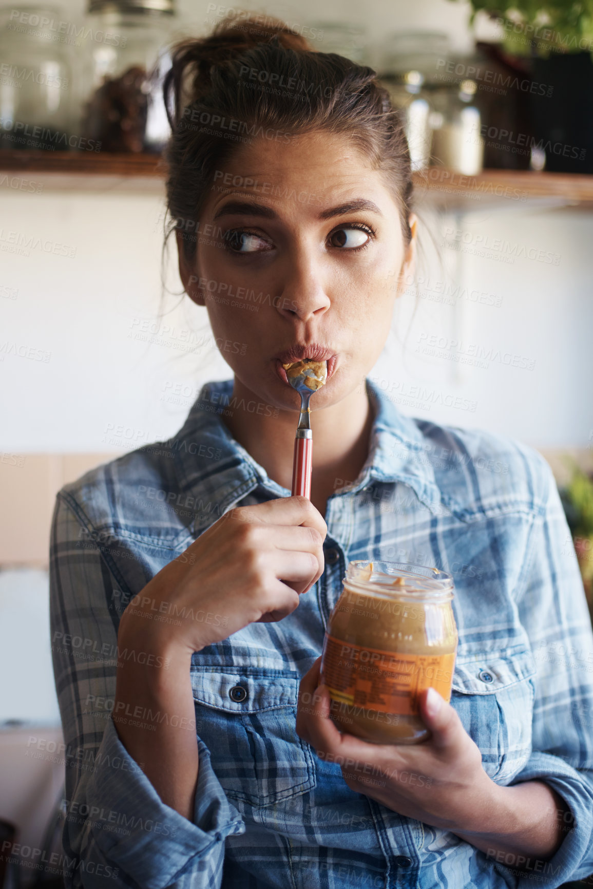 Buy stock photo Shot of a beautiful young woman eating peanut butter out of the jar with a spoon