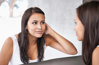 Buy stock photo A cropped shot of a beautiful young woman deciding on a hair style in front of her bathroom mirror