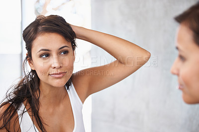 Buy stock photo A cropped shot of a beautiful young woman deciding on a hair style in front of her bathroom mirror