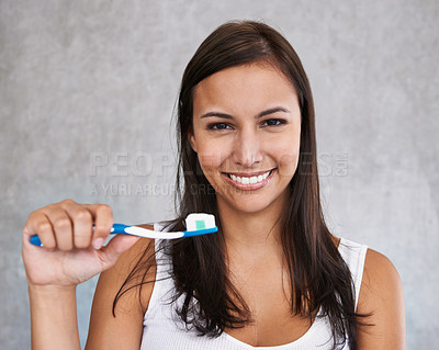 Buy stock photo An isolated portrait of a young woman happily brushing her teeth