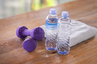 Buy stock photo A shot of dumbells, water bottles and a towel on a wooden table