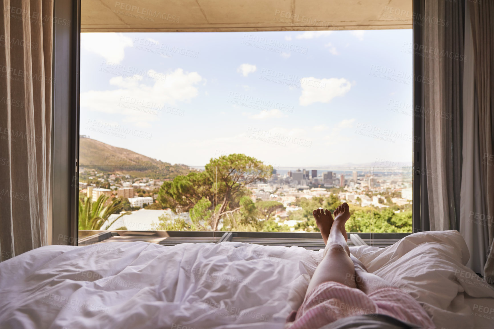 Buy stock photo Window view, bedroom, relax and legs on holiday, morning relaxation and wake up. Apartment, stress relief and the feet of a person during a vacation with views of nature and the city from bed