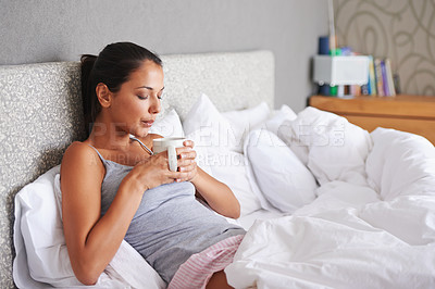 Buy stock photo Attractive young woman blowing the hot steam off her morning coffee