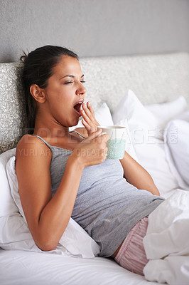 Buy stock photo Woman, bedroom and coffee in morning with yawn for waking up, tired and exhausted at home. Female person, relax and sleepy gesture with mug in apartment for day off, weekend and beverage on pillow