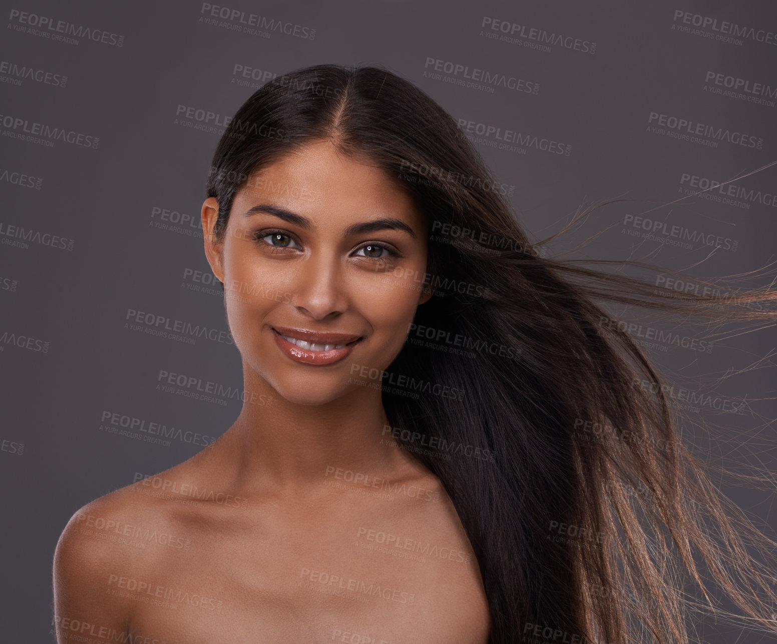 Buy stock photo Hair care, wind and portrait of happy woman with beauty, shine and skincare isolated on a gray studio background. Hairstyle, cosmetics and face of Indian model in salon with makeup at hairdresser