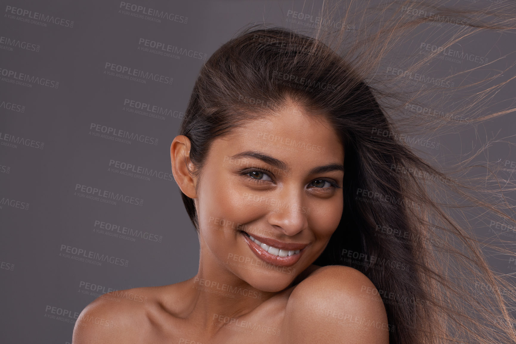 Buy stock photo Hair, wind and portrait of happy woman in makeup for beauty or shine isolated on a gray studio background. Hairstyle, skincare and face of Indian model in salon with cosmetics at hairdresser for care