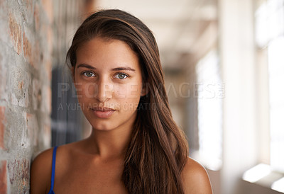 Buy stock photo Portrait, serious and woman by brick wall for confidence or casual fashion in corridor alone. Face, skin or young student, girl and hair of female person in hallway for profile picture in Argentina