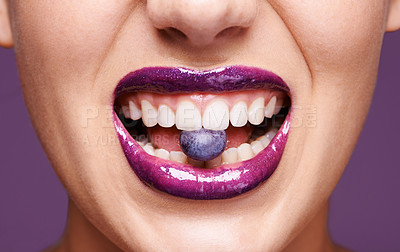 Buy stock photo Beauty, lipstick and woman with blueberry in mouth, organic makeup and creativity with shiny cosmetic product. Vegan, eco friendly and purple lip gloss for aesthetic with fruit on studio background