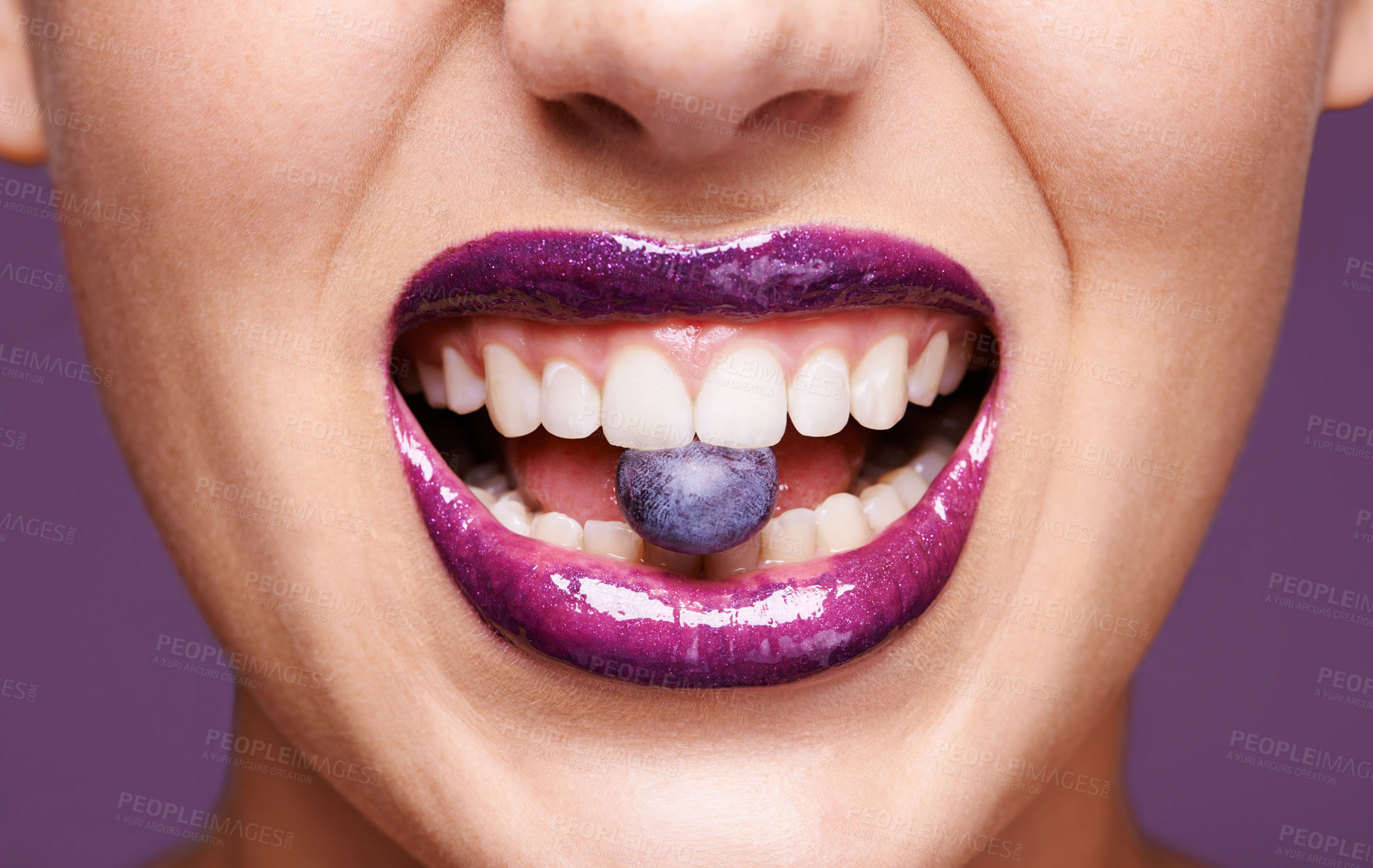 Buy stock photo Beauty, lipstick and woman with blueberry in mouth, organic makeup and creativity with shiny cosmetic product. Vegan, eco friendly and purple lip gloss for aesthetic with fruit on studio background