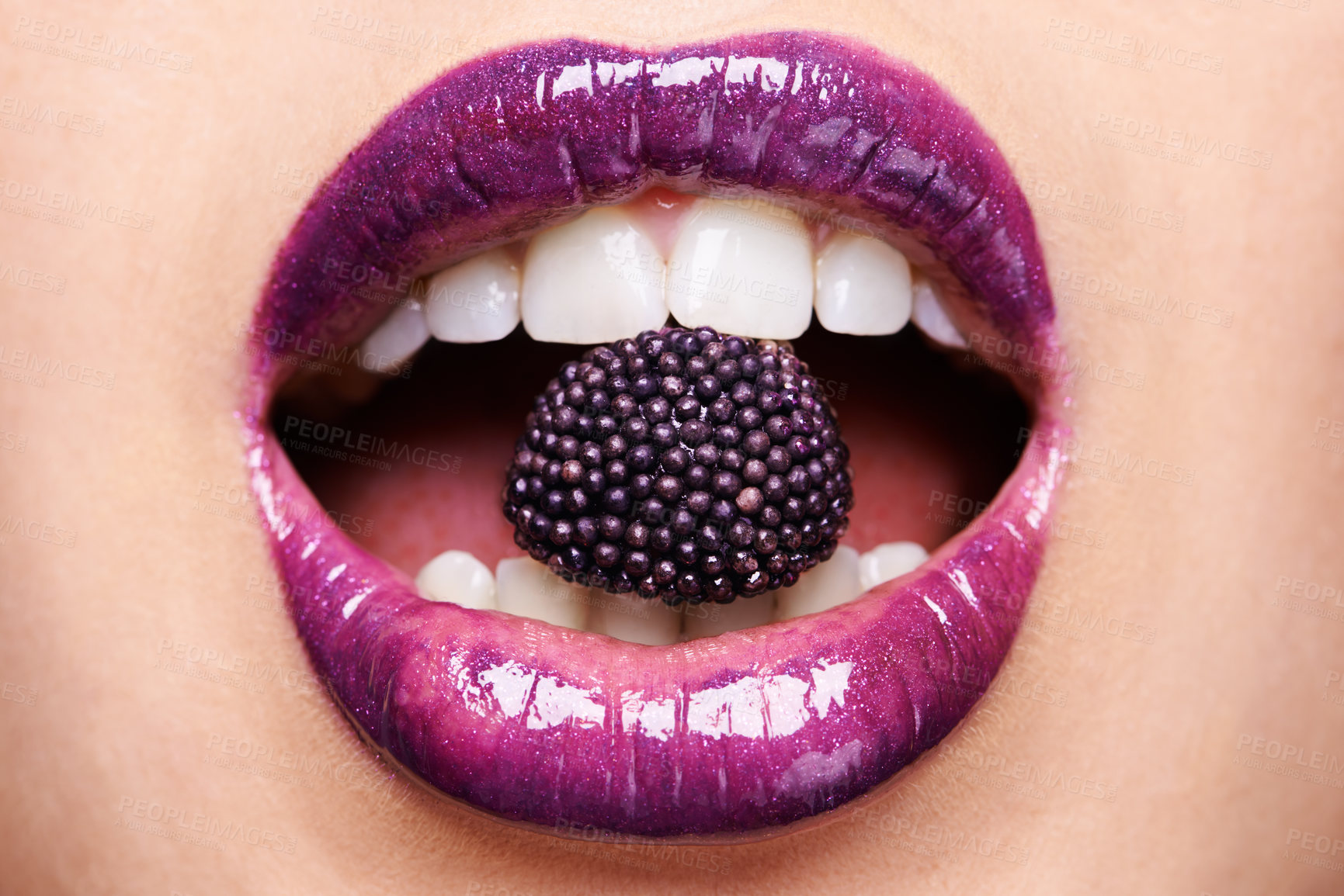 Buy stock photo Shot of a woman wearing purple lipstick and biting into a purple sweet