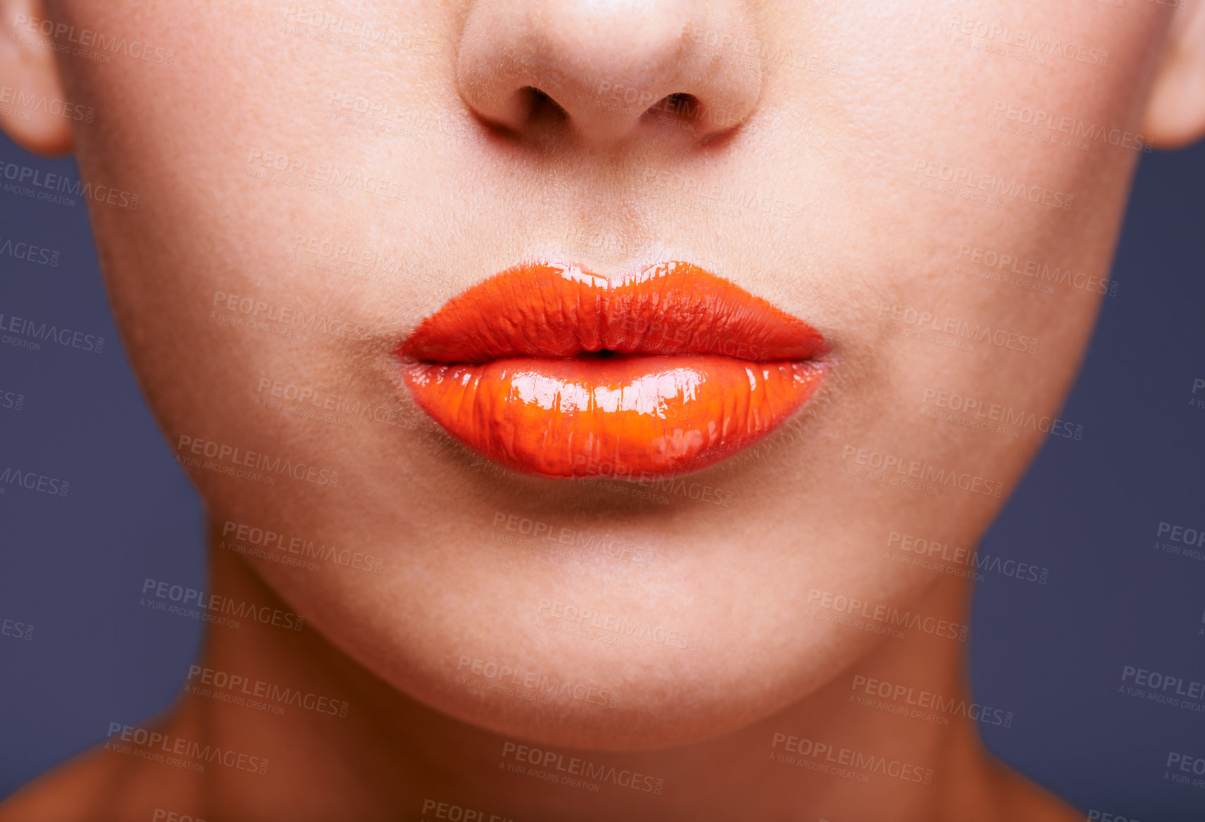 Buy stock photo Cropped shot of a woman's lips covered in shiny orange lipstick