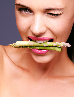 Buy stock photo Portrait of a woman biting on a bunch of asparagus in studio