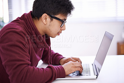Buy stock photo Young man, focus and typing with laptop for research, development or creative startup on table at office desk. Male person, nerd or geek with vision on computer for email, networking or communication