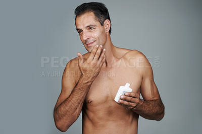 Buy stock photo Man, moisturizer and skincare lotion in studio for hygiene treatment for facial wellness, grey background or mockup space. Male person, product and healthy dermatology for anti aging, cream or apply