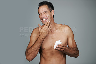 Buy stock photo Man, smile and moisturizer lotion in studio for skincare treatment for facial wellness, grey background or mockup space. Male person, product and healthy dermatology for anti aging, cream or apply