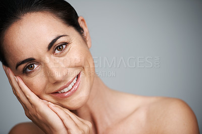 Buy stock photo Woman, studio and smile with hand, skin and care for treatment and proud. Model, cosmetics and natural with lip gloss, glow or aesthetic for antiaging confidence portrait isolated on grey background