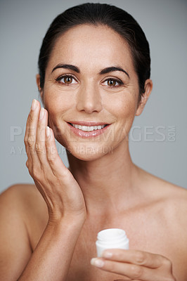 Buy stock photo Portrait, happy woman and apply cream for skincare in studio isolated on a gray background. Face, cosmetics and mature model with moisturizer in jar for dermatology, beauty or hydration for antiaging