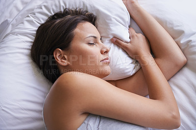 Buy stock photo Cropped shot of a young woman lying on a bed