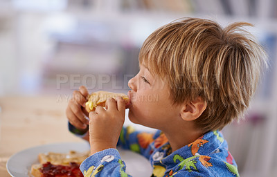 Buy stock photo Food, breakfast and boy eating a sandwich in morning, pyjamas and home for nutrition. Children, hungry and meal for young male for lunch, childhood development and bread for health and wellness 