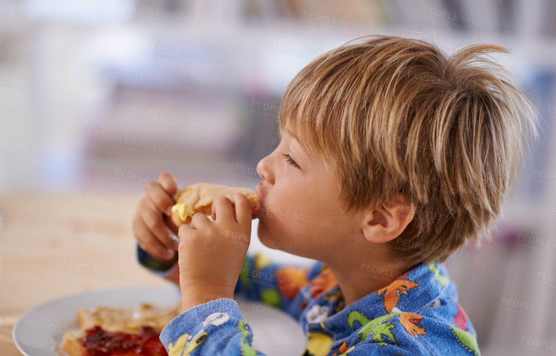 Buy stock photo Food, breakfast and boy eating a sandwich in morning, pyjamas and home for nutrition. Children, hungry and meal for young male for lunch, childhood development and bread for health and wellness 