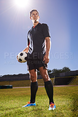 Buy stock photo Shot of a young footballer standing on a field with a ball in his hands