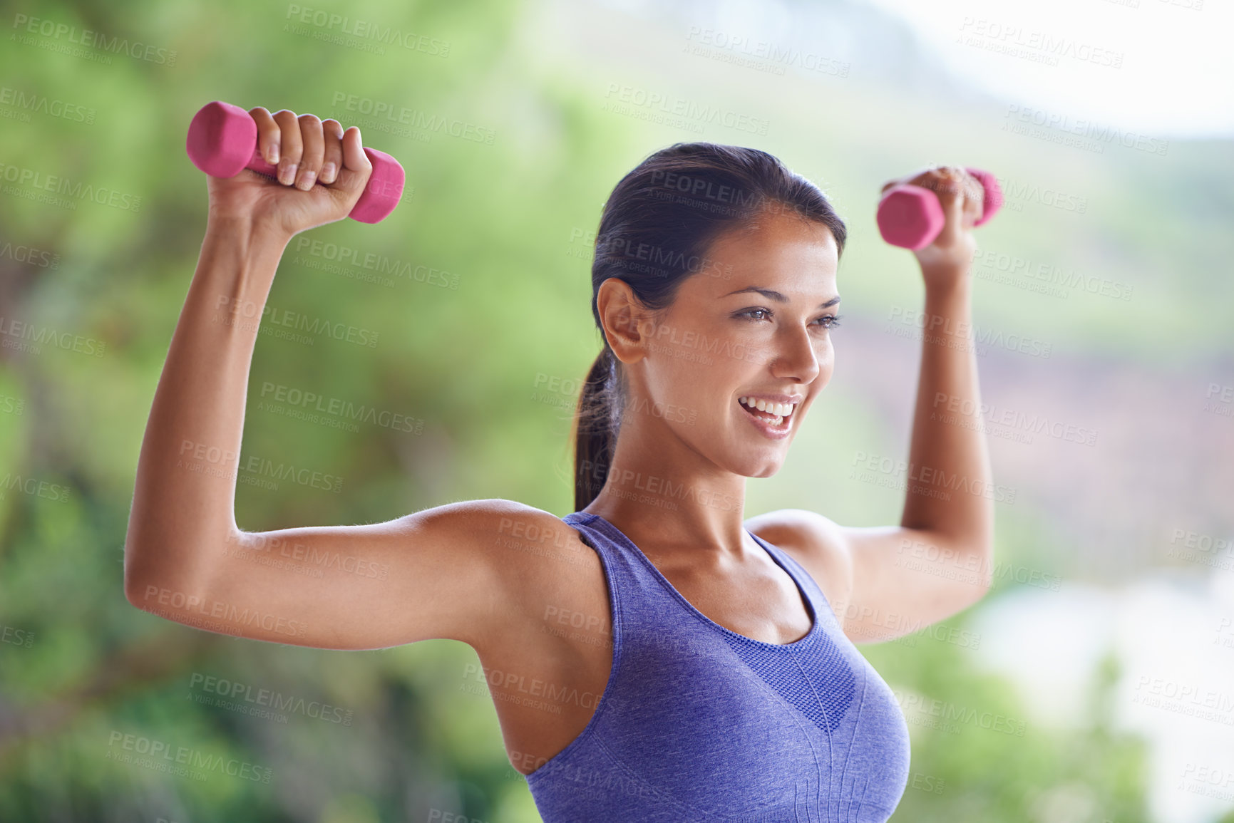 Buy stock photo A beautiful young woman lifting dumbbells outdoors