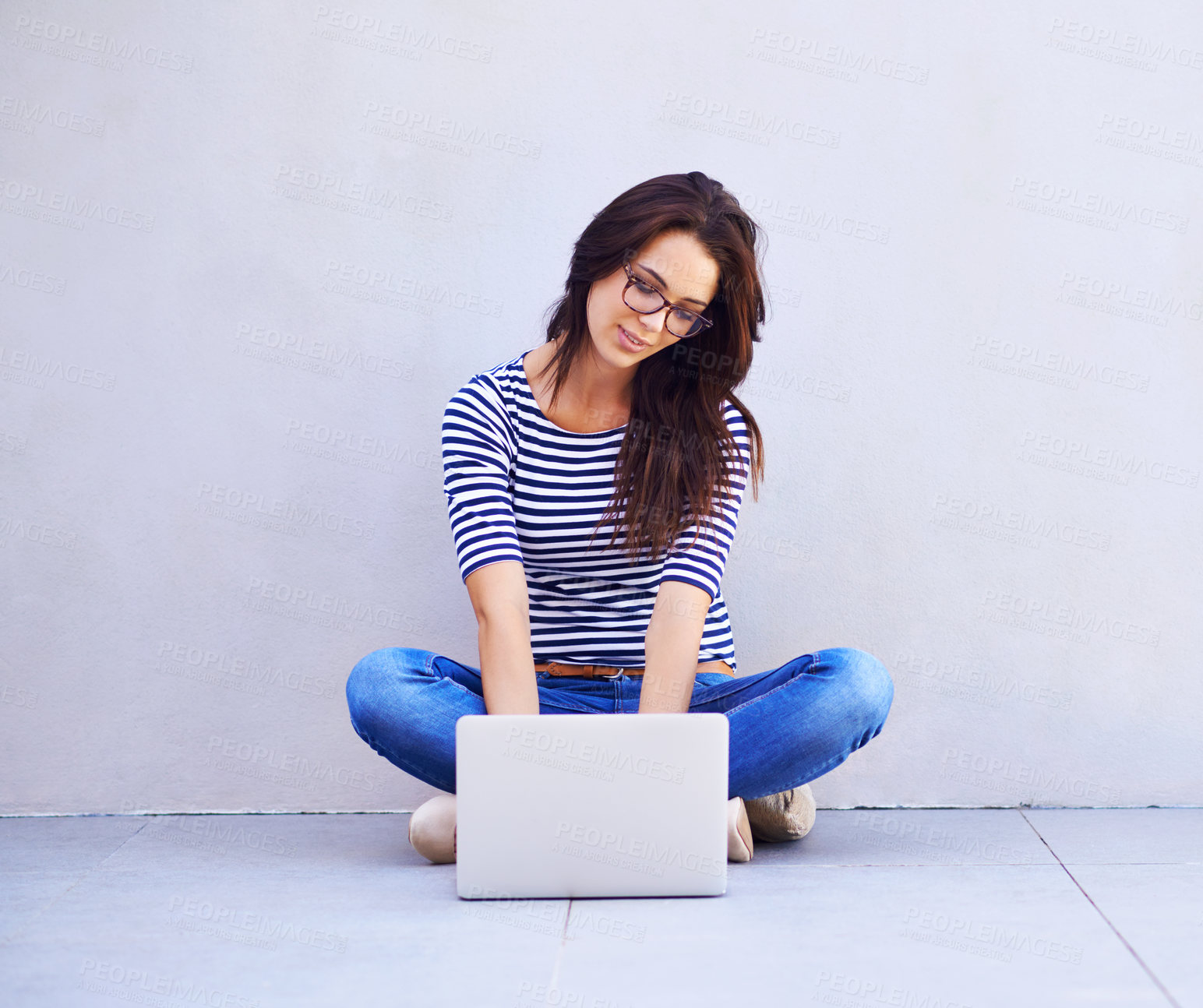 Buy stock photo Full length shot of an attractive young woman sitting cross legged using a laptop