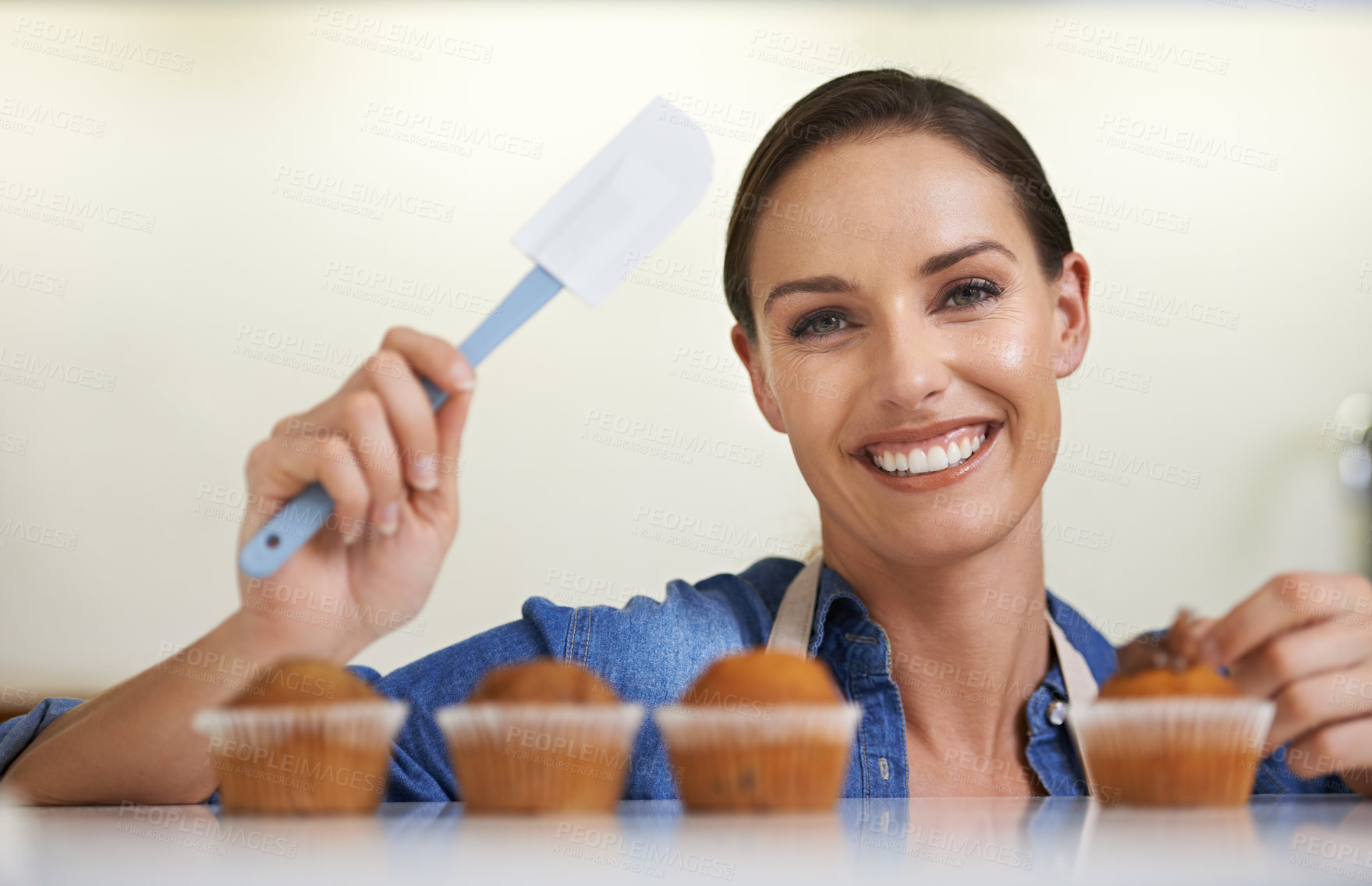 Buy stock photo Baking, cupcakes and portrait of woman with spatula in kitchen with sweet chocolate frosting for dessert. Cooking, smile and young female baker working on muffins with culinary tool at apartment.
