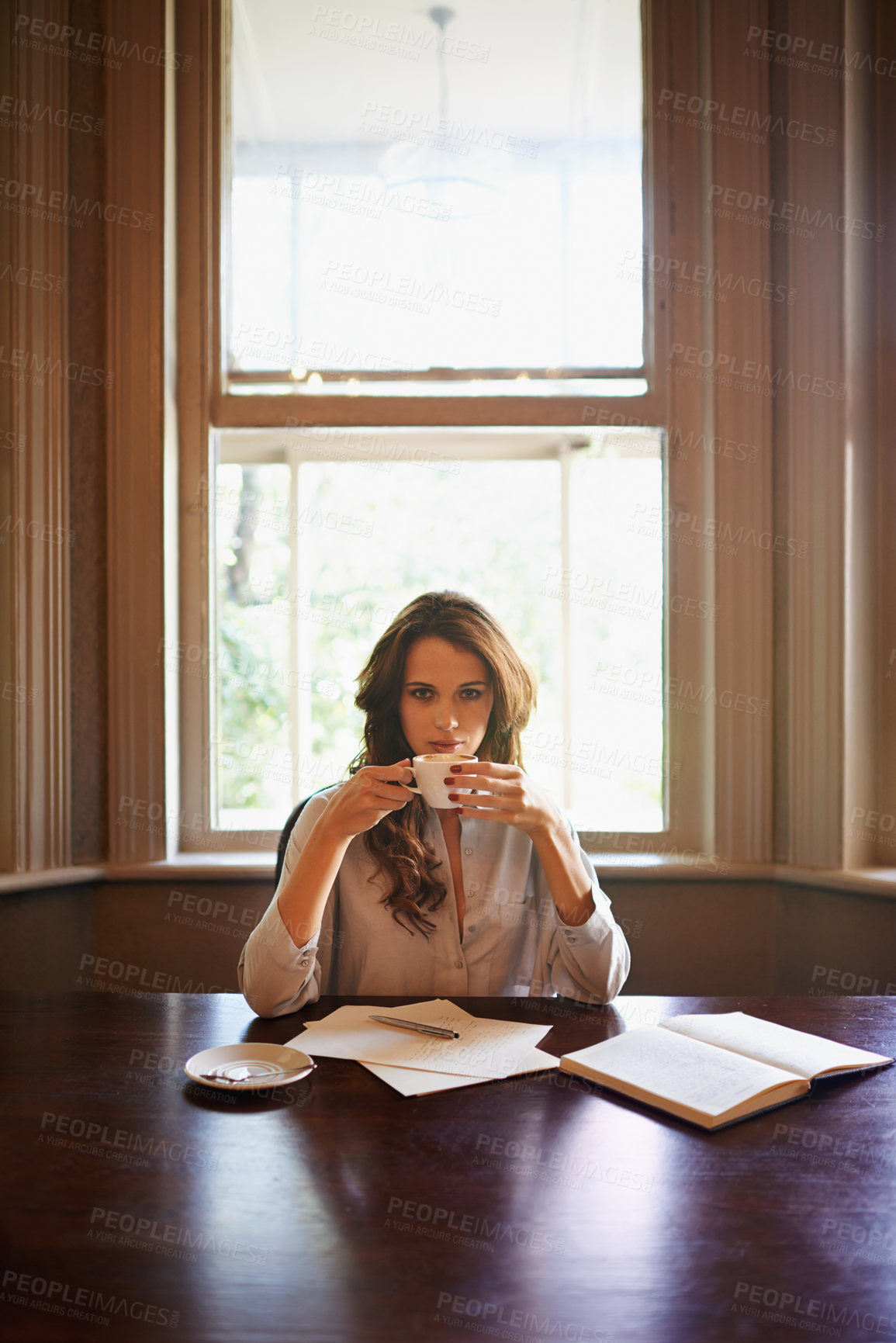 Buy stock photo Portrait of an attractive young author enjoying a cup of coffee while writing indoors