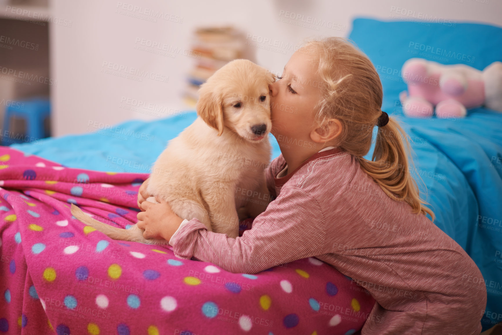 Buy stock photo A cropped shot of a little girl kissing her puppy while it sits on her bed
