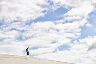 Buy stock photo Hike, dunes and sky with male person in nature for adventure, walk and desert landscape with clouds. Fitness, travel and nomad man people in Sahara, outdoor and hiking in dry climate and scenery