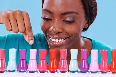 Buy stock photo A young african woman looking over a row of colorful nail polish