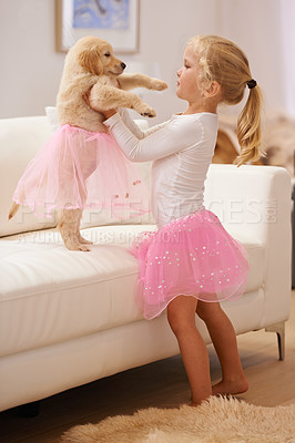 Buy stock photo A little girl dressing her puppy in a tutu