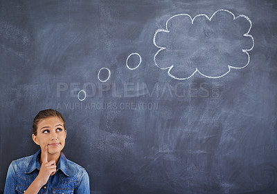Buy stock photo Shot of a young woman  looking thoughtfully at a thought bubble