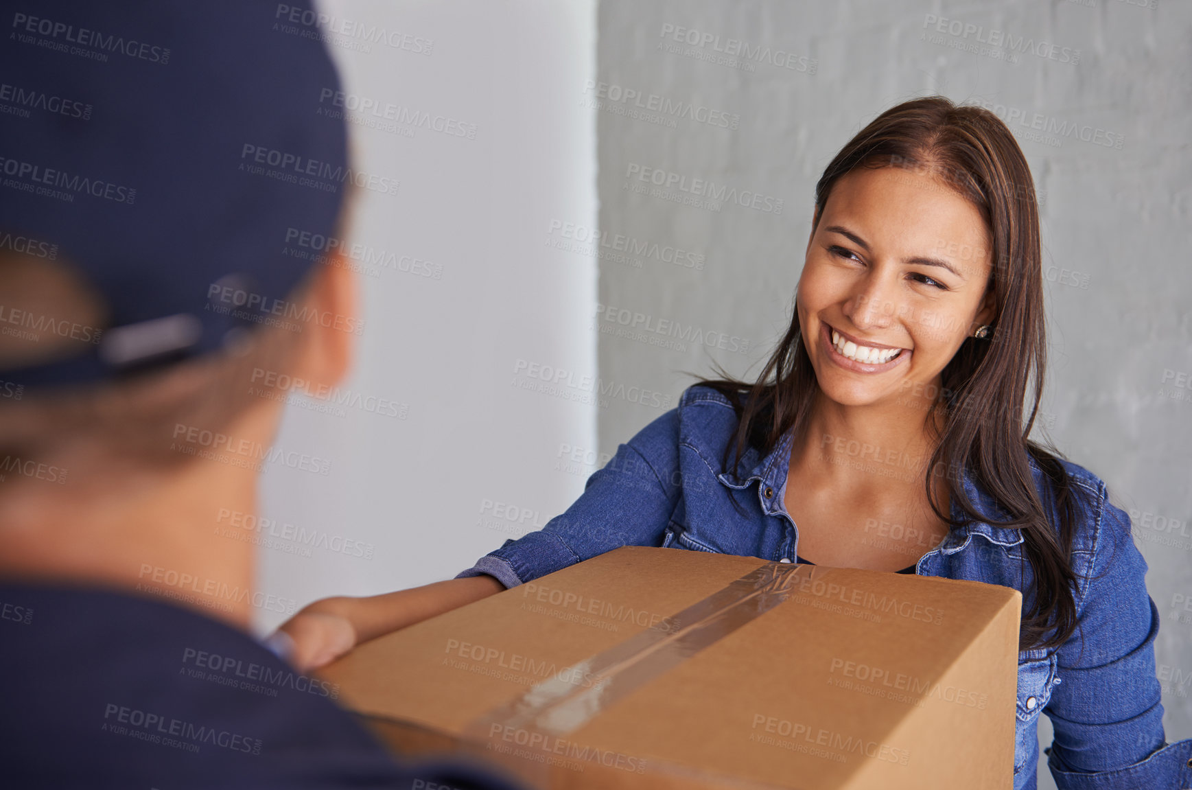 Buy stock photo A beautiful young woman smiling at the camera as she takes a box from a mover
