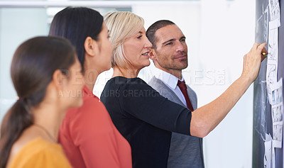 Buy stock photo A team of businesspeople drawing up a storyboard on a chalkboard in the office