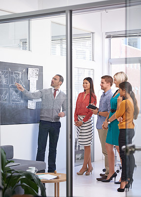Buy stock photo Creative man, chalkboard and coaching with team for storyboard, development or meeting at office. Speaker talking to group of employees for project planning, production or presentation in startup