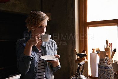 Buy stock photo Shot of an attractive young woman drinking tea in her kitchen