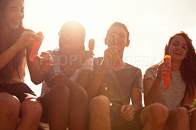 Buy stock photo Shot of a group of teenage friends eating ice-cream on a sunny day