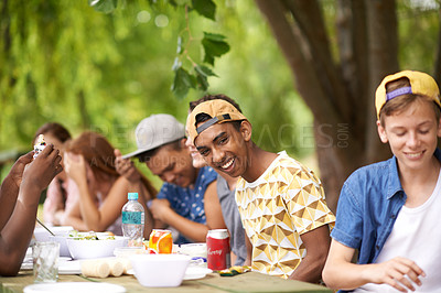 Buy stock photo Shot of a group of teenage friends hanging out while on a picnic at the park
