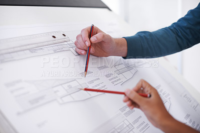 Buy stock photo Cropped shot of two architects working on a building plan at a drawing board