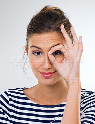 Buy stock photo Shot of a beautiful young woman using her fingers to make a ring around her eye